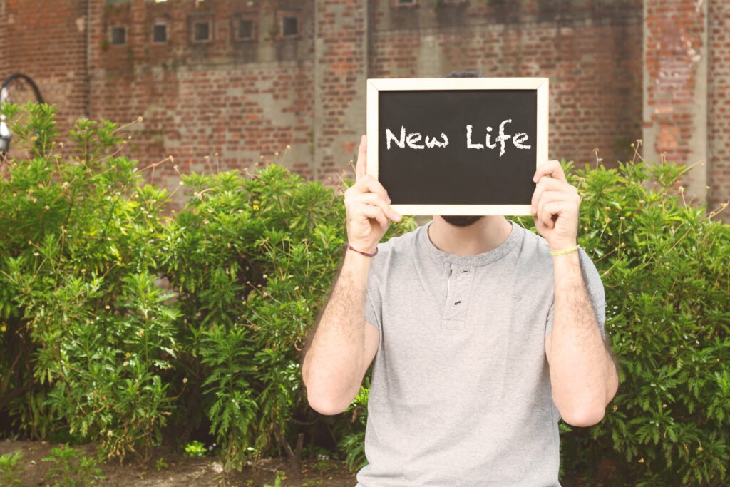 Person holding a New Life sign representing hope, sobriety, and transformation through Serenity Street Foundation’s affordable sober living program.